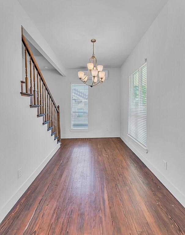 interior space featuring beamed ceiling, dark wood-type flooring, a wealth of natural light, and a chandelier