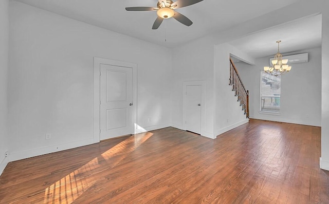 empty room featuring a wall mounted air conditioner, dark hardwood / wood-style floors, and ceiling fan with notable chandelier