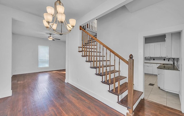 stairway featuring sink, ceiling fan with notable chandelier, and hardwood / wood-style flooring