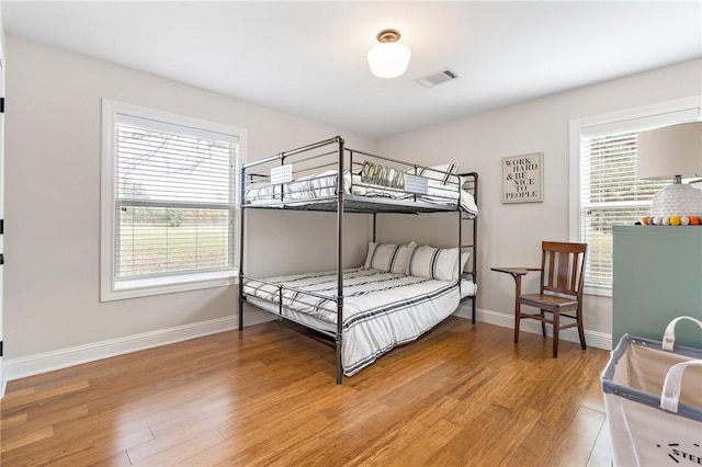 bedroom with hardwood / wood-style flooring and multiple windows