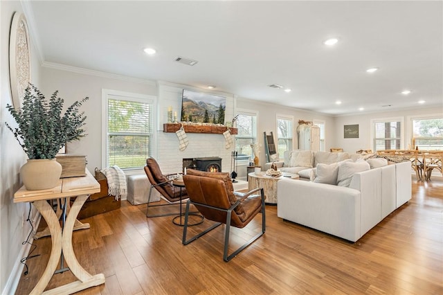 living room with a large fireplace, light hardwood / wood-style floors, and crown molding