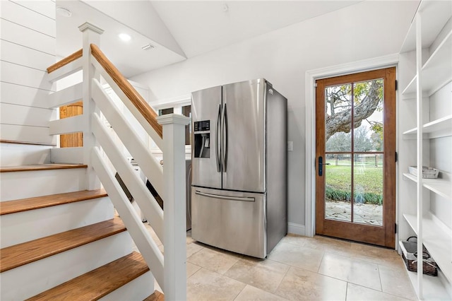 kitchen featuring stainless steel fridge with ice dispenser, light tile patterned floors, and vaulted ceiling