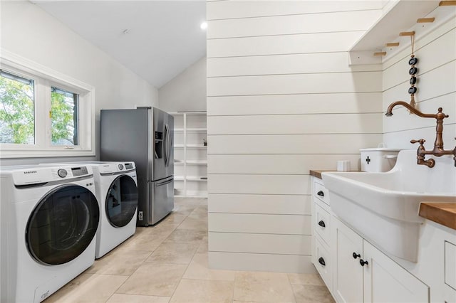 laundry area with sink, washing machine and dryer, wooden walls, and light tile patterned flooring