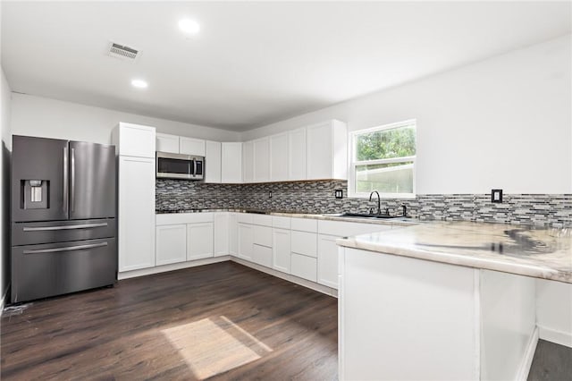 kitchen with appliances with stainless steel finishes, dark hardwood / wood-style floors, white cabinetry, and sink