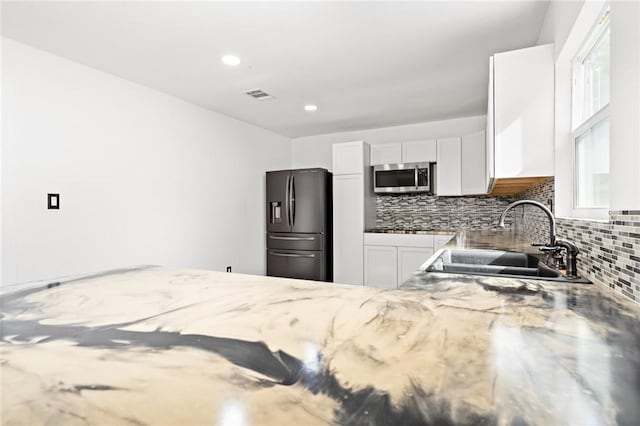 kitchen featuring backsplash, sink, light stone counters, white cabinetry, and stainless steel appliances