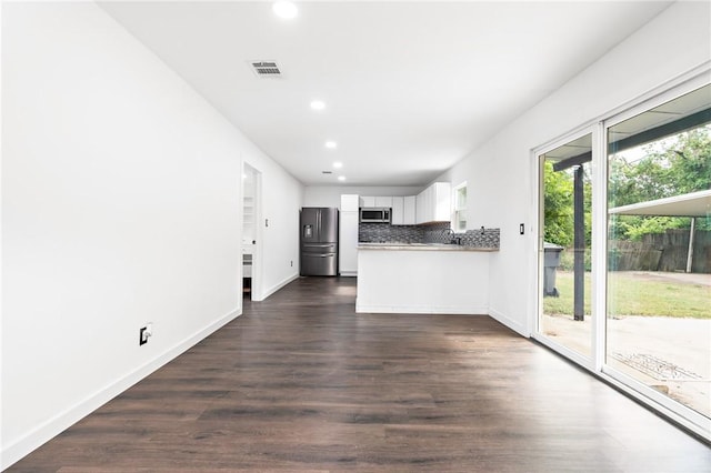 kitchen with kitchen peninsula, dark hardwood / wood-style flooring, tasteful backsplash, stainless steel appliances, and white cabinetry