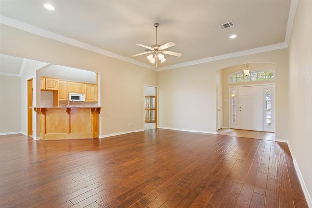 unfurnished living room with ceiling fan, dark hardwood / wood-style flooring, and ornamental molding