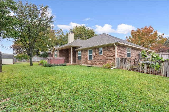 back of property with a lawn and a hot tub