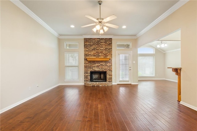 unfurnished living room featuring ceiling fan with notable chandelier, dark hardwood / wood-style flooring, a brick fireplace, and ornamental molding