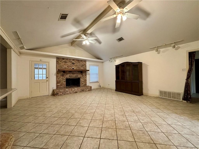 unfurnished living room featuring ceiling fan, light tile patterned floors, a brick fireplace, rail lighting, and lofted ceiling with beams