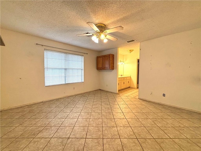 unfurnished room featuring a textured ceiling, ceiling fan, and light tile patterned floors