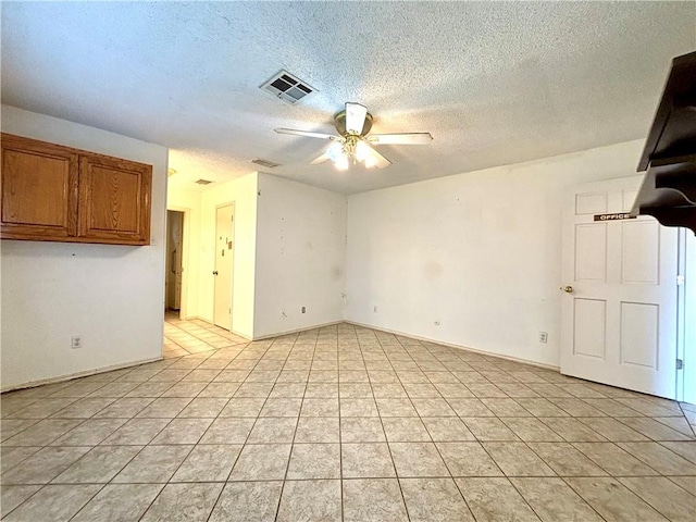 empty room with a textured ceiling, ceiling fan, and light tile patterned floors