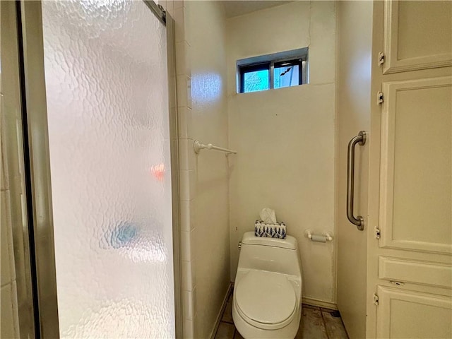 bathroom with toilet and a shower with door