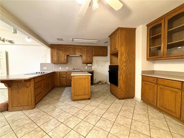 kitchen featuring black appliances, light tile patterned floors, ceiling fan, a kitchen bar, and a kitchen island