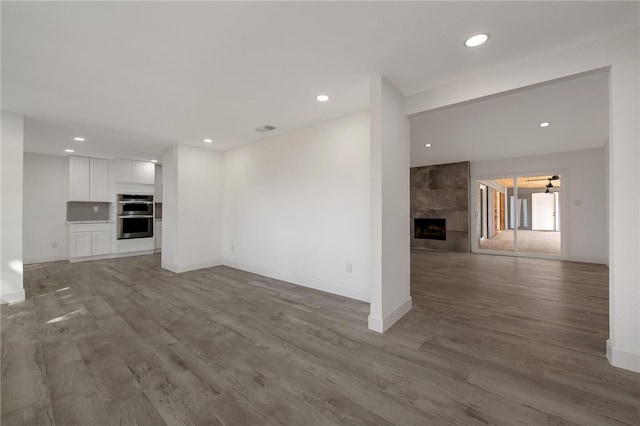 unfurnished living room featuring hardwood / wood-style flooring and a tiled fireplace