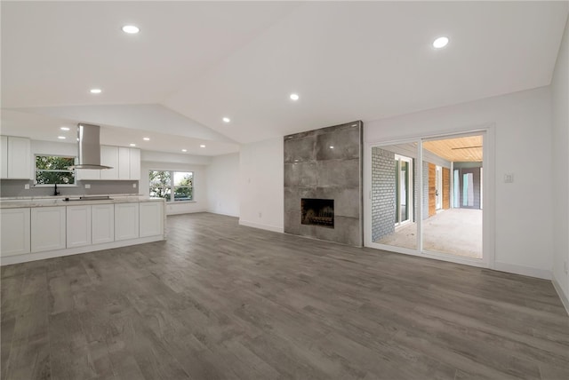 unfurnished living room featuring a tile fireplace, dark hardwood / wood-style flooring, and vaulted ceiling