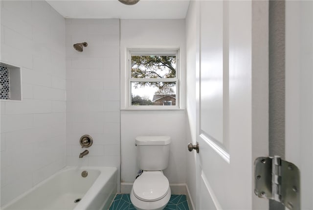 bathroom with tile patterned flooring, toilet, and tiled shower / bath