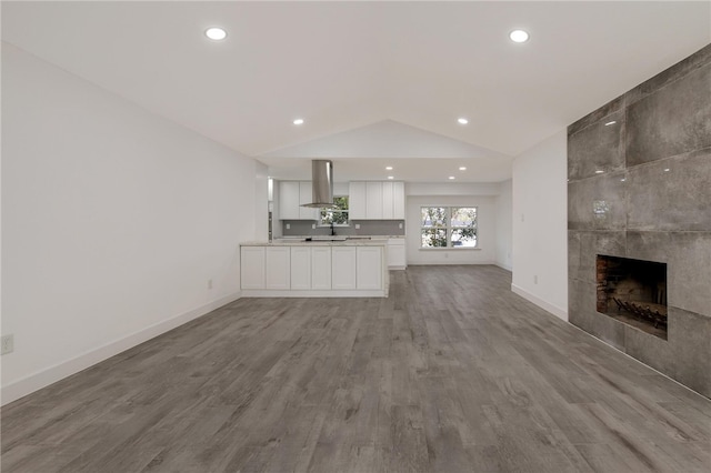 unfurnished living room featuring a fireplace, light hardwood / wood-style flooring, and lofted ceiling