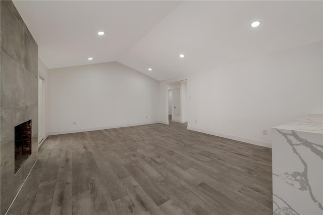 unfurnished living room with a fireplace, hardwood / wood-style floors, and vaulted ceiling