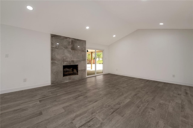 unfurnished living room with vaulted ceiling, a tile fireplace, and dark hardwood / wood-style floors