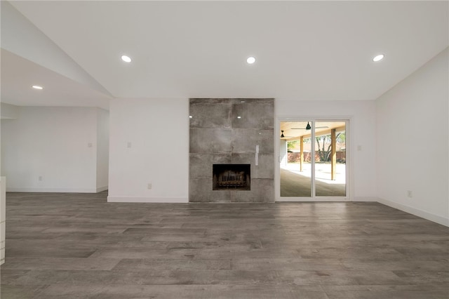 unfurnished living room with a fireplace, dark wood-type flooring, and lofted ceiling