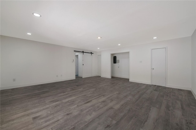 spare room featuring a barn door and dark hardwood / wood-style floors