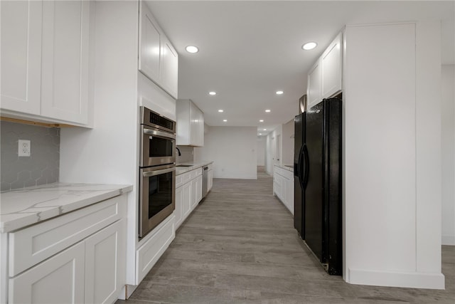 kitchen featuring light stone countertops, tasteful backsplash, stainless steel appliances, light hardwood / wood-style flooring, and white cabinetry