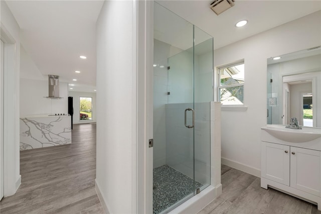 bathroom with hardwood / wood-style floors, a wealth of natural light, and a shower with shower door