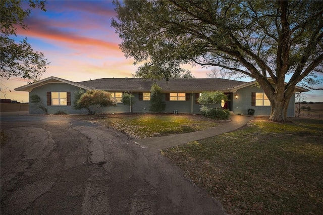 ranch-style house with driveway and a front lawn