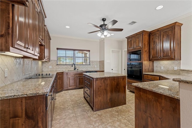 kitchen featuring black appliances, light stone countertops, ornamental molding, and a center island