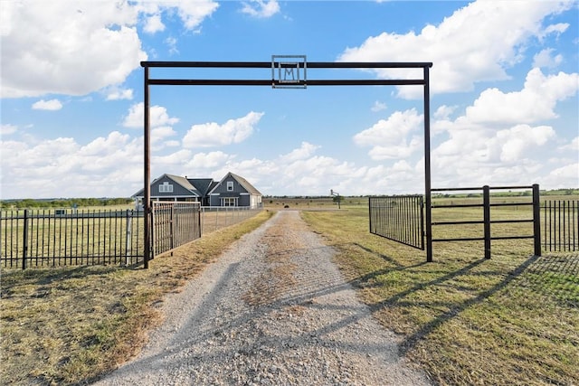 view of road featuring gravel driveway, a rural view, and a gated entry