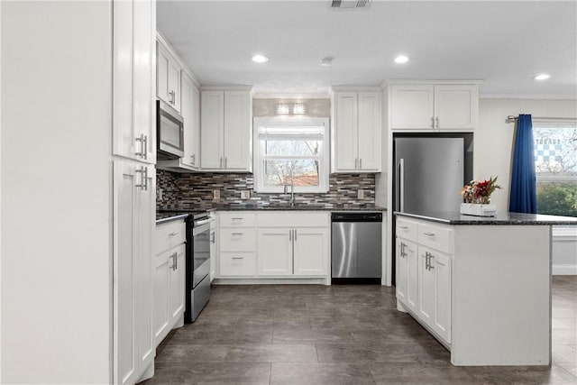 kitchen featuring stainless steel appliances, white cabinets, a sink, and backsplash