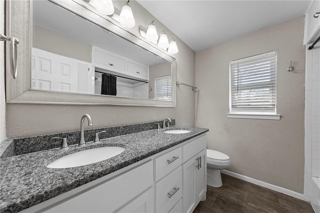 full bathroom with baseboards, a sink, toilet, and double vanity