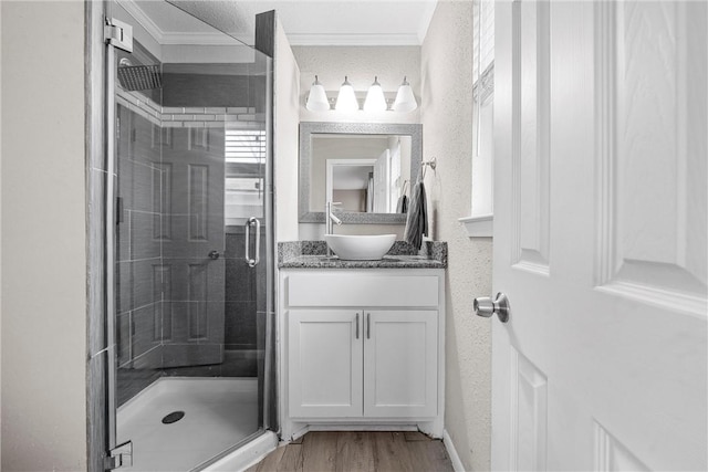 full bathroom with a stall shower, ornamental molding, wood finished floors, and vanity