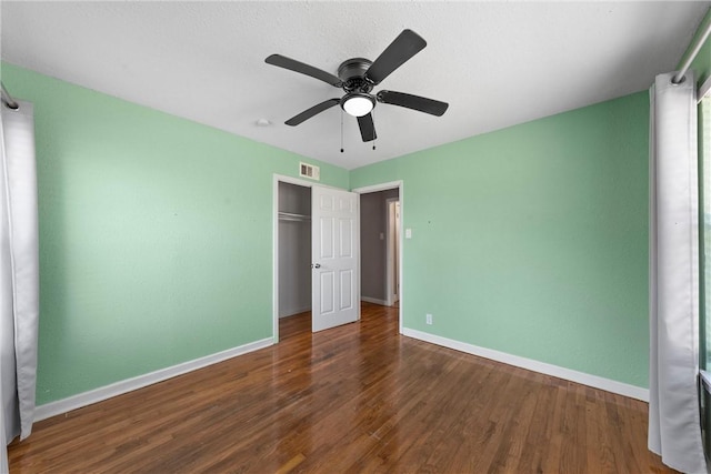 unfurnished bedroom featuring a closet, wood finished floors, visible vents, and baseboards