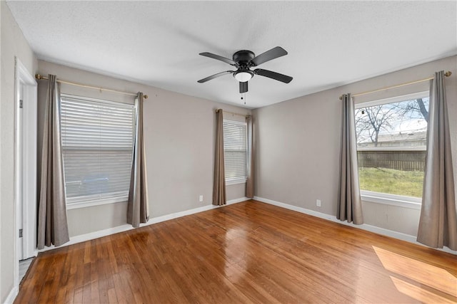 spare room featuring a textured ceiling, hardwood / wood-style floors, a ceiling fan, and baseboards