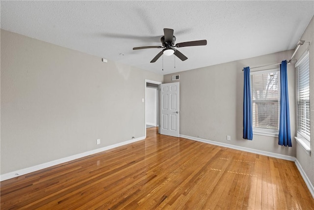 spare room with visible vents, light wood-style floors, a ceiling fan, a textured ceiling, and baseboards