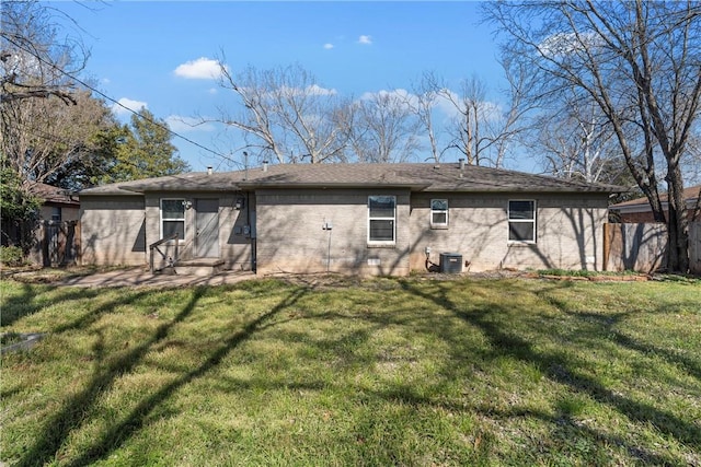 rear view of house featuring brick siding, fence, cooling unit, and a yard