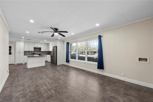 kitchen with tasteful backsplash, appliances with stainless steel finishes, open floor plan, and ornamental molding