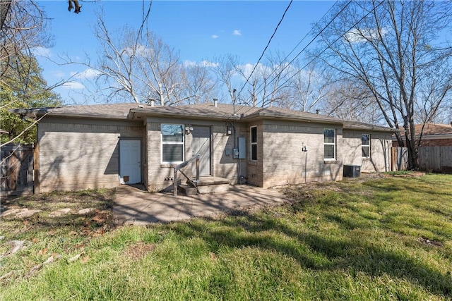 rear view of house with a yard, central AC unit, fence, and brick siding