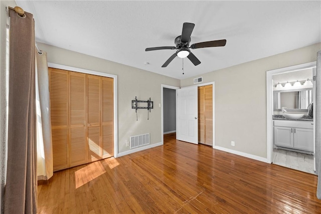 unfurnished bedroom with multiple closets, visible vents, and wood finished floors