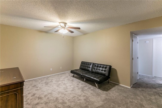 living area with a textured ceiling, carpet floors, and ceiling fan