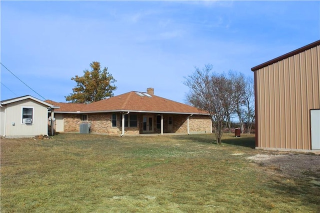 rear view of property featuring central AC unit and a lawn