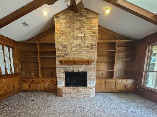 unfurnished living room with built in shelves, a healthy amount of sunlight, carpet floors, and lofted ceiling with beams