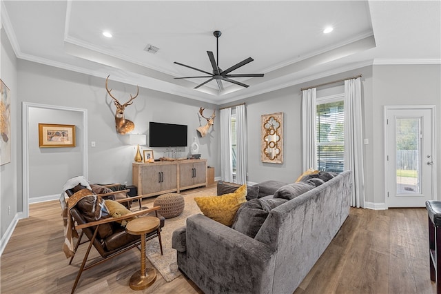 living area featuring a raised ceiling, visible vents, and wood finished floors