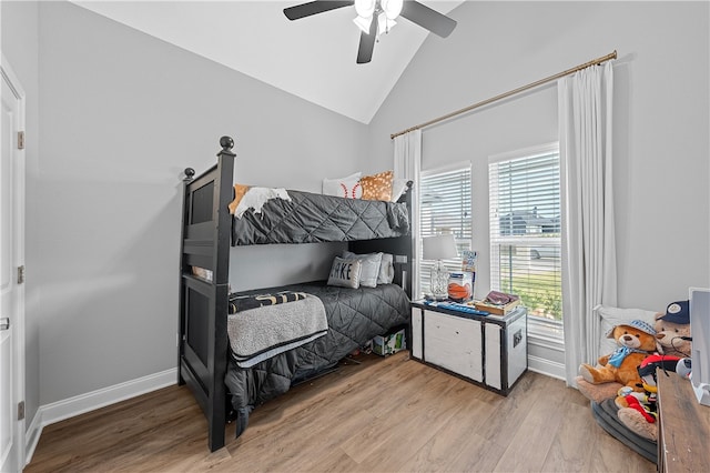 bedroom featuring multiple windows, vaulted ceiling, baseboards, and wood finished floors