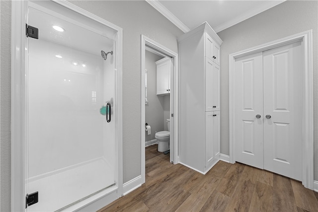 full bathroom featuring ornamental molding, a stall shower, wood finished floors, and toilet