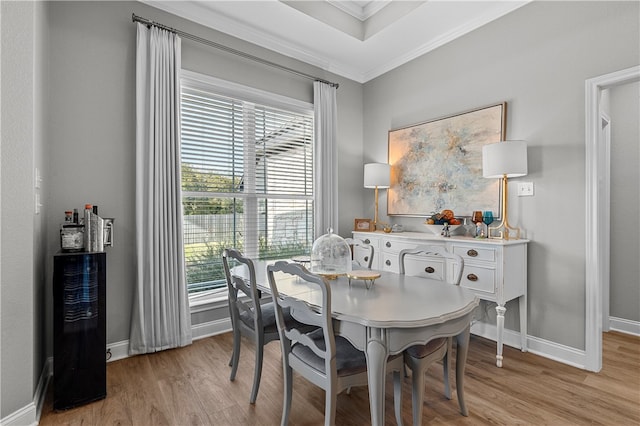 dining space featuring baseboards, a healthy amount of sunlight, crown molding, and light wood finished floors