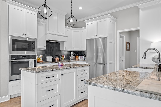 kitchen featuring stainless steel appliances, ornamental molding, a sink, and light stone counters