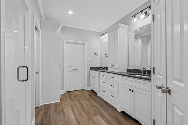 bathroom with double vanity, wood finished floors, a sink, and crown molding